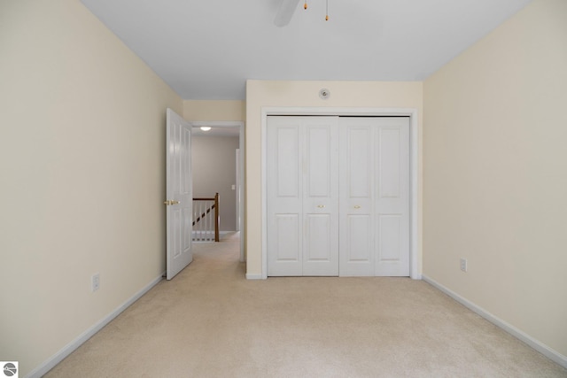 unfurnished bedroom featuring baseboards, a closet, and light carpet