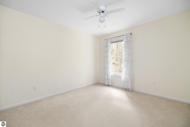 spare room with baseboards, a ceiling fan, and light colored carpet