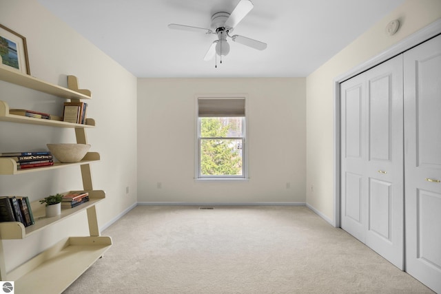 unfurnished bedroom featuring baseboards, visible vents, light carpet, and ceiling fan