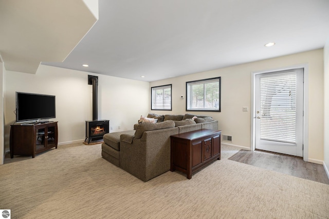 living area with baseboards, visible vents, and a wood stove