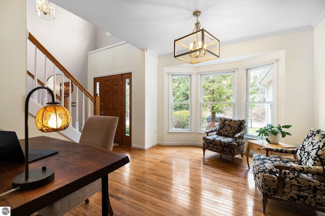 interior space with ornamental molding, baseboards, stairway, light wood finished floors, and a notable chandelier