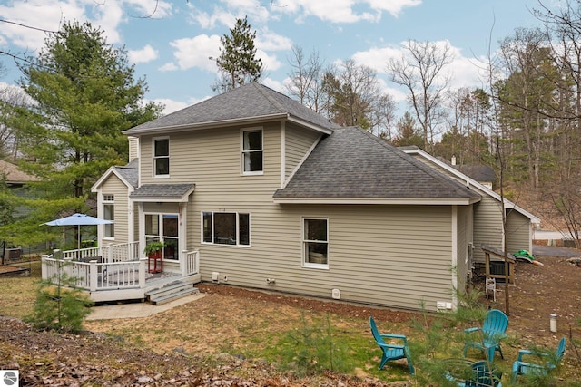 rear view of property with a shingled roof and a wooden deck