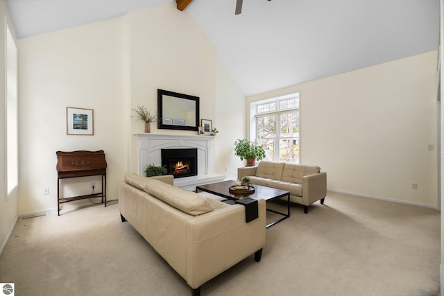 living area featuring light carpet, beamed ceiling, a lit fireplace, high vaulted ceiling, and a ceiling fan