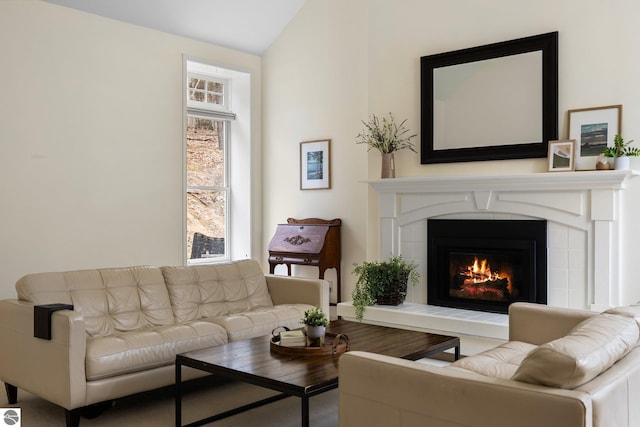 sitting room featuring a healthy amount of sunlight, a tile fireplace, and lofted ceiling