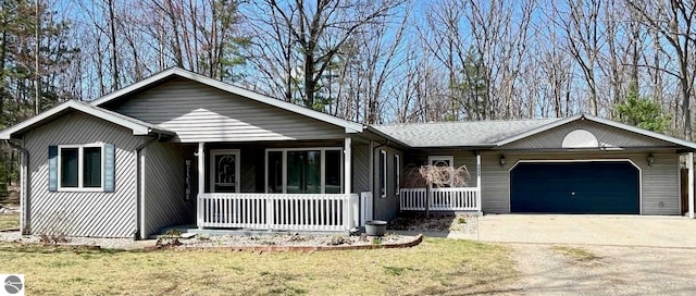 single story home with a garage, a front lawn, a porch, and driveway