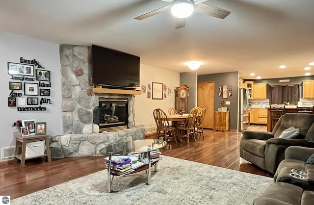 living area with a ceiling fan, visible vents, a fireplace, wood finished floors, and recessed lighting