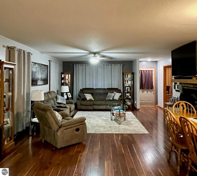 living area with a ceiling fan and dark wood-style floors