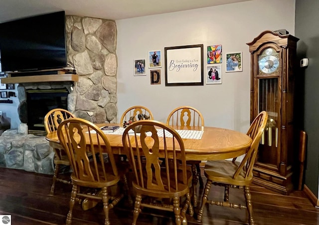 dining space with a stone fireplace and wood finished floors