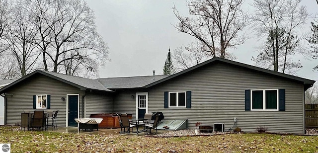 rear view of property featuring fence, a patio, and a hot tub
