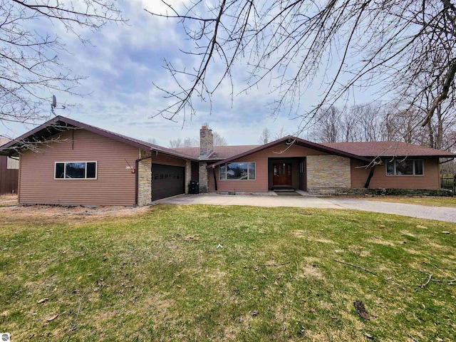 ranch-style house featuring a chimney, a front yard, concrete driveway, an attached garage, and stone siding