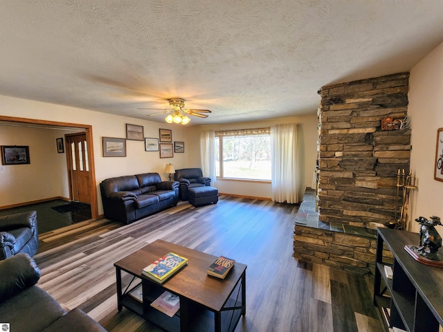 living area with a textured ceiling, ceiling fan, baseboards, and wood finished floors