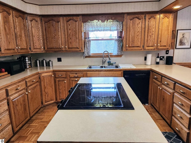 kitchen featuring a sink, light countertops, black appliances, and brown cabinets
