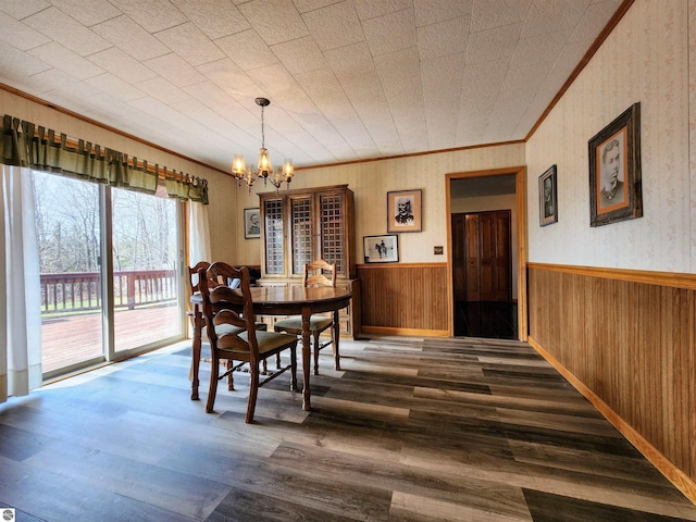 dining area featuring an inviting chandelier, a wainscoted wall, crown molding, and dark wood-style floors