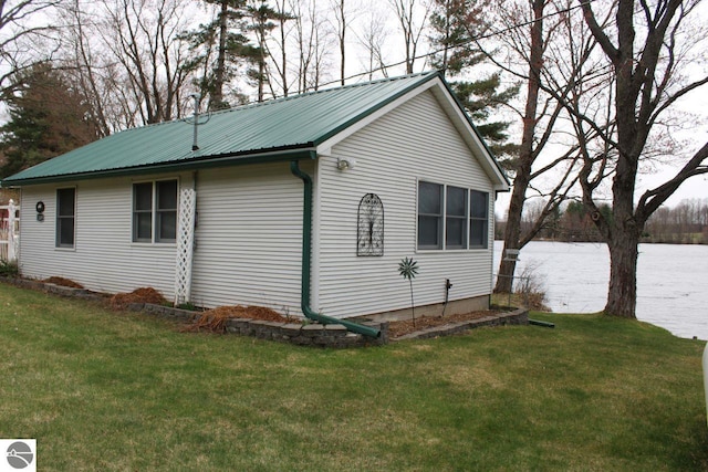 view of property exterior with a lawn and metal roof