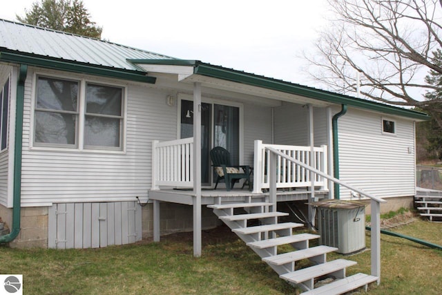 back of house featuring central AC, covered porch, crawl space, metal roof, and a lawn