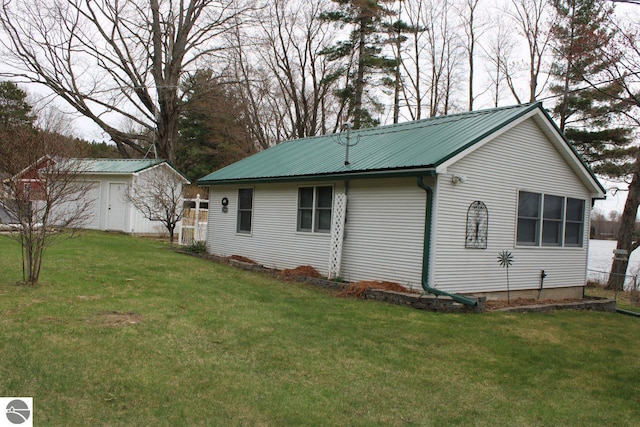 view of side of home featuring an outdoor structure, a yard, and metal roof