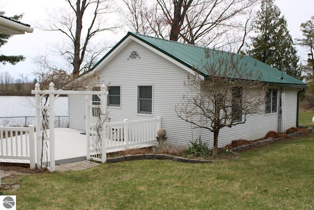 view of home's exterior featuring a wooden deck, a yard, and metal roof