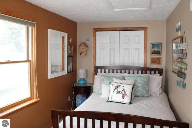 bedroom with a closet, attic access, and a textured ceiling