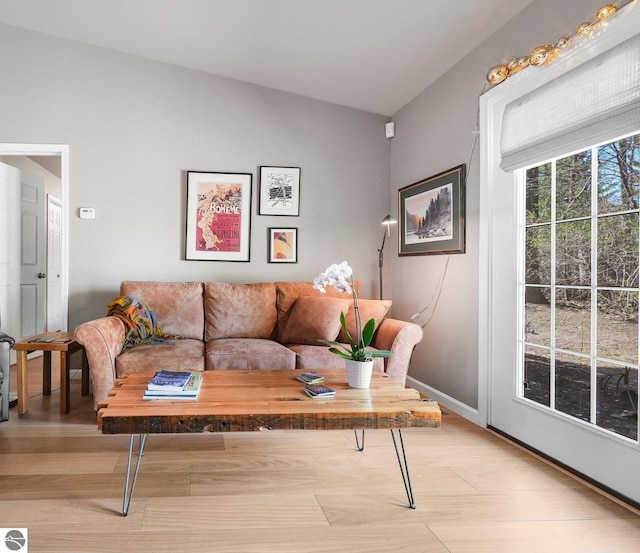living room with baseboards, light wood-style flooring, and lofted ceiling