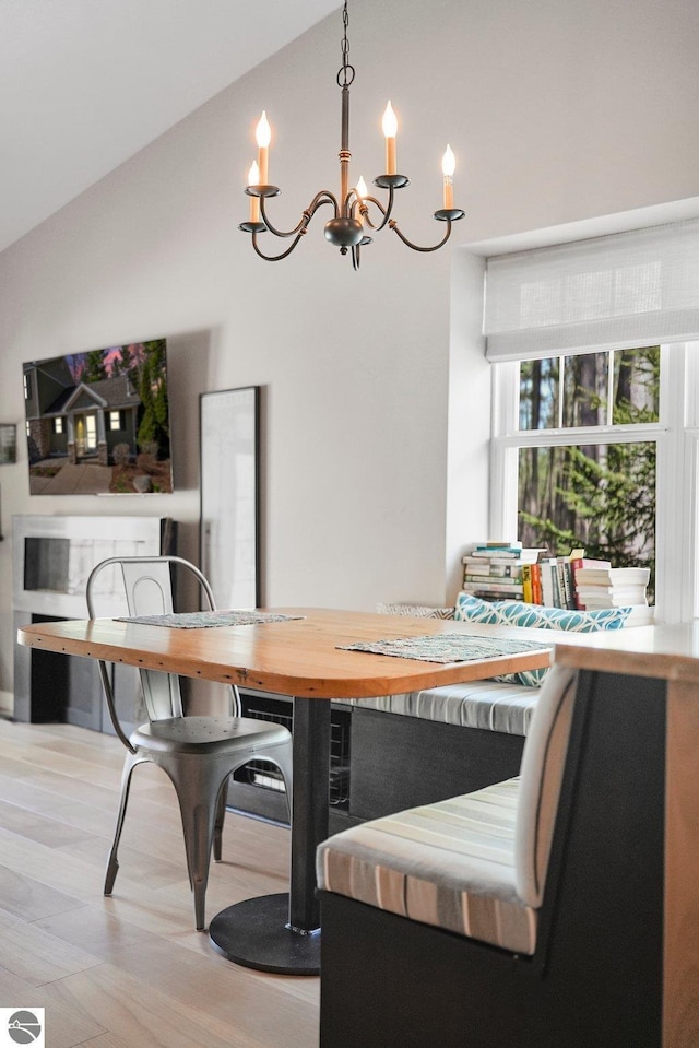 dining area featuring wood finished floors, lofted ceiling, and a chandelier