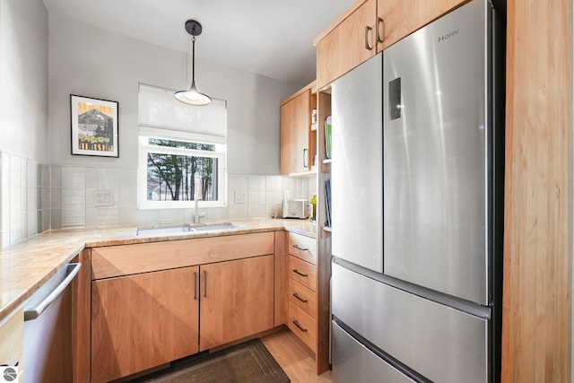 kitchen featuring pendant lighting, tasteful backsplash, a sink, light countertops, and stainless steel appliances