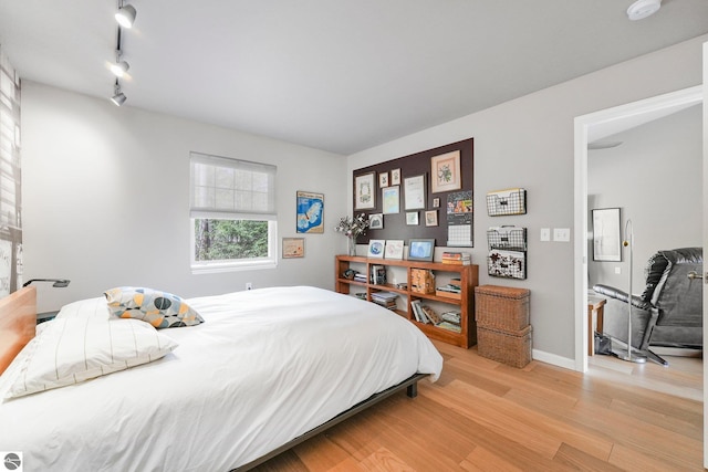 bedroom with baseboards, light wood-style flooring, and track lighting