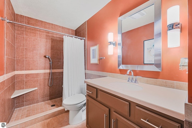full bathroom with vanity, a tile shower, and toilet