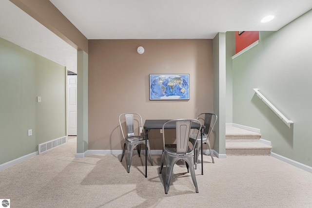 carpeted dining space with baseboards, visible vents, and stairway