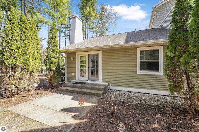exterior space featuring roof with shingles, a patio area, and a chimney
