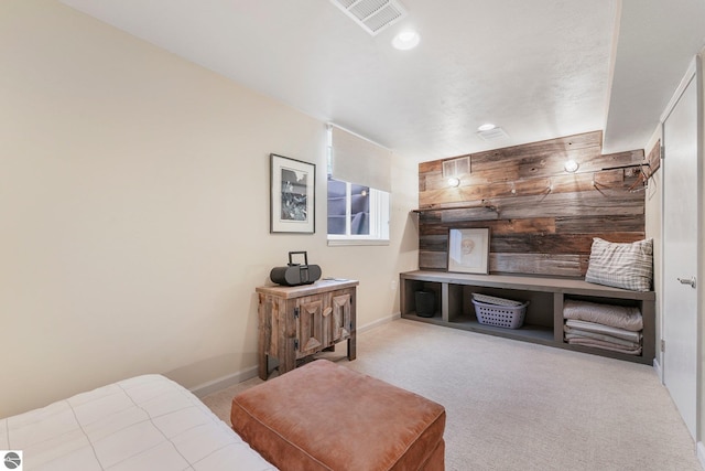 bedroom featuring wood walls, visible vents, baseboards, and carpet