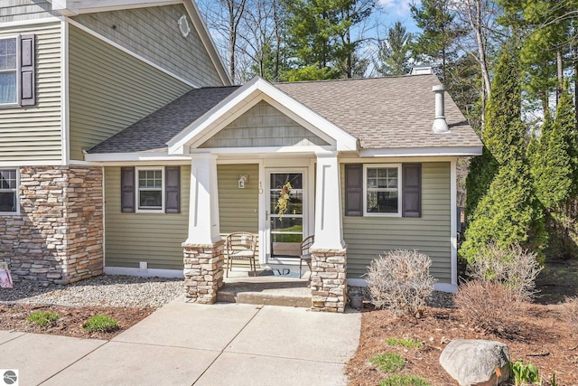 craftsman-style house featuring a porch, a shingled roof, and stone siding
