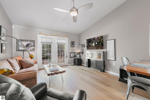 living area featuring baseboards, a ceiling fan, light wood finished floors, and a fireplace