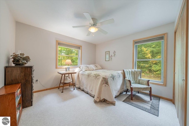 bedroom with a ceiling fan, baseboards, and light colored carpet