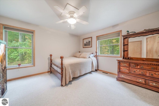 carpeted bedroom featuring a ceiling fan, baseboards, and multiple windows