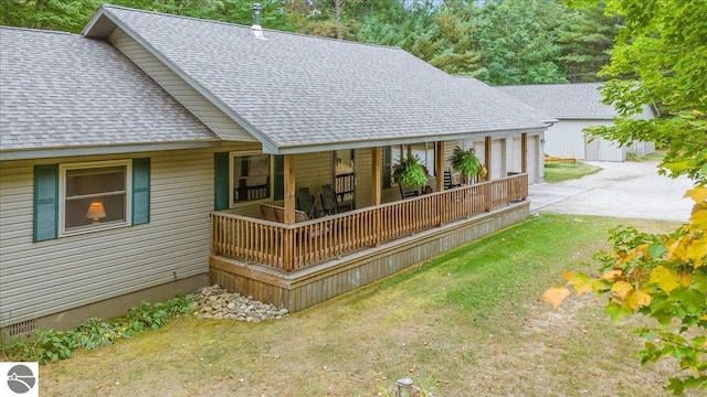 rear view of property with roof with shingles, covered porch, and a lawn