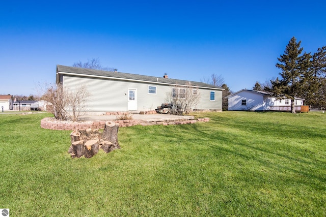 2280 NW Tamara Rd, Kalkaska, MI 49646 - back of house featuring a lawn and a patio