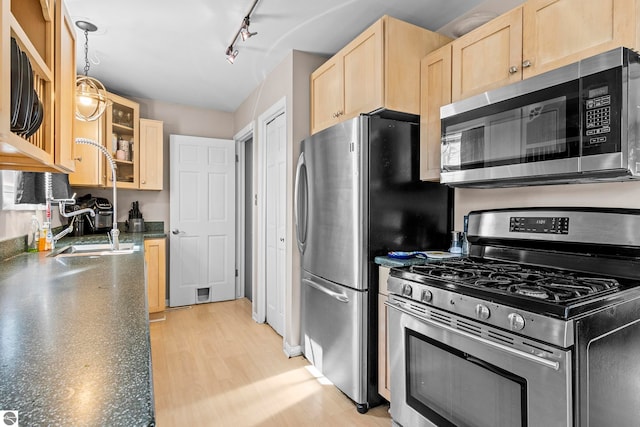 2280 NW Tamara Rd, Kalkaska, MI 49646 - kitchen with a sink, glass insert cabinets, light brown cabinets, stainless steel appliances, and light wood-style flooring