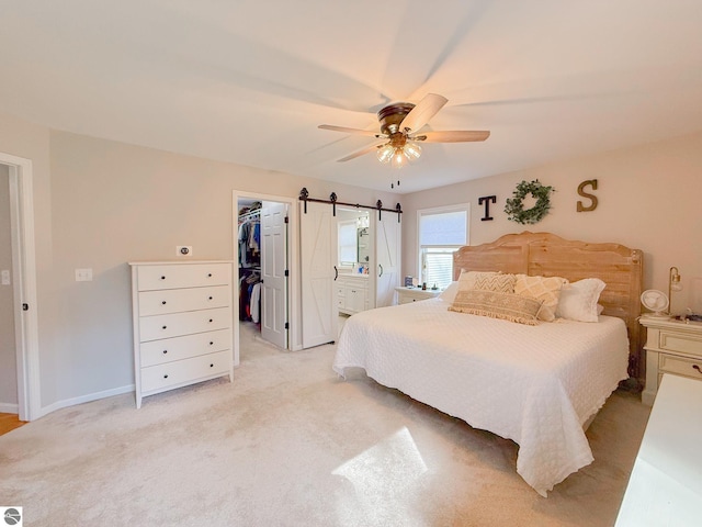 bedroom with a walk in closet, a ceiling fan, baseboards, ensuite bathroom, and a closet
