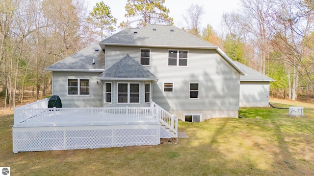 rear view of house featuring a lawn, a shingled roof, and a deck