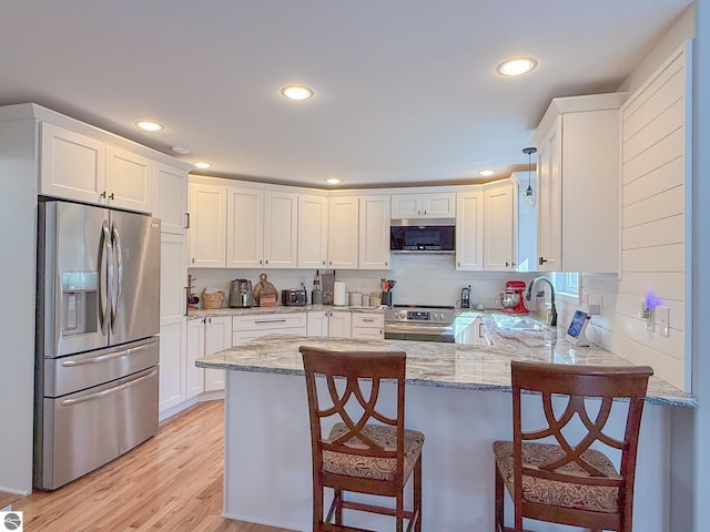 kitchen featuring white cabinets, stainless steel appliances, and a peninsula