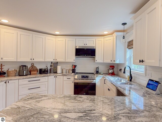 kitchen with a sink, appliances with stainless steel finishes, light stone counters, and white cabinetry