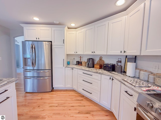 kitchen with white cabinets, recessed lighting, range, and stainless steel fridge