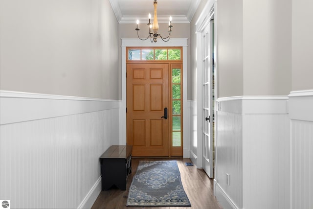 foyer entrance featuring a wainscoted wall, ornamental molding, wood finished floors, and a chandelier