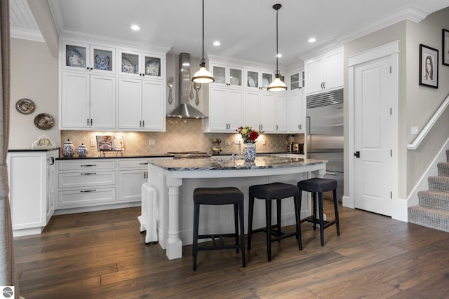 kitchen with stainless steel built in fridge, ornamental molding, wall chimney exhaust hood, and white cabinets