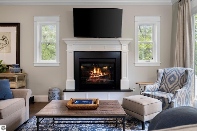 living room featuring a glass covered fireplace, baseboards, ornamental molding, and dark wood-style floors