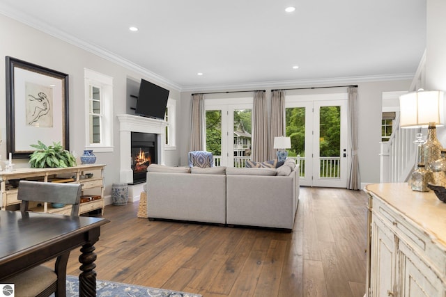 living area featuring ornamental molding, a glass covered fireplace, recessed lighting, hardwood / wood-style flooring, and french doors