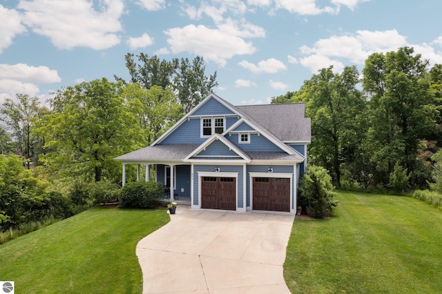 craftsman inspired home with covered porch, a shingled roof, driveway, and a front yard