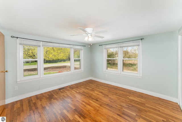 unfurnished room featuring baseboards, ceiling fan, wood finished floors, and visible vents
