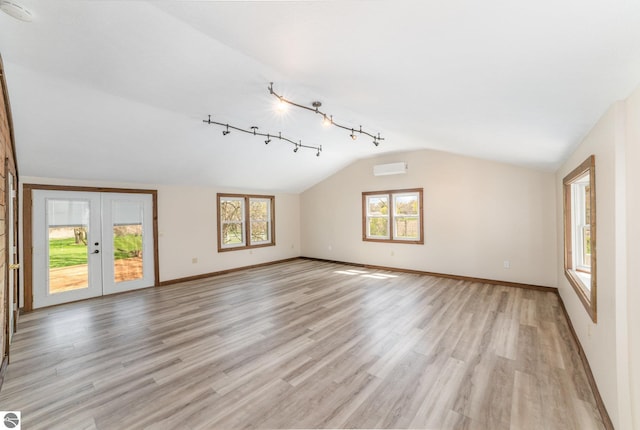 unfurnished living room with french doors, baseboards, light wood-type flooring, vaulted ceiling, and a wall mounted AC