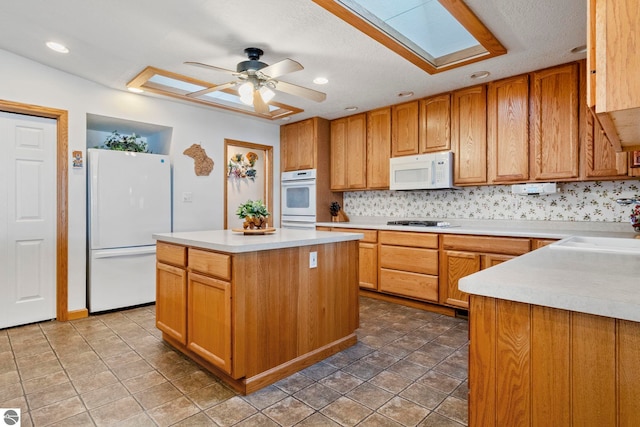 5449 E Shore Dr NE, Kalkaska, MI 49646 - kitchen featuring white appliances, light countertops, a ceiling fan, a kitchen island, and a sink